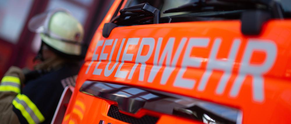 Ein Feuerwehrmann steht neben einem Einsatzfahrzeug (gestellte Szene)