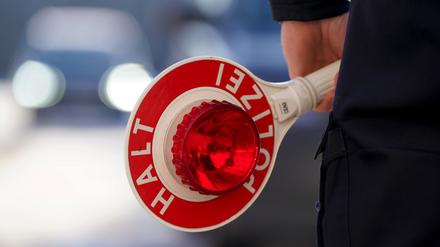 Ein Polizist hält eine Anhaltekelle in der Hand.