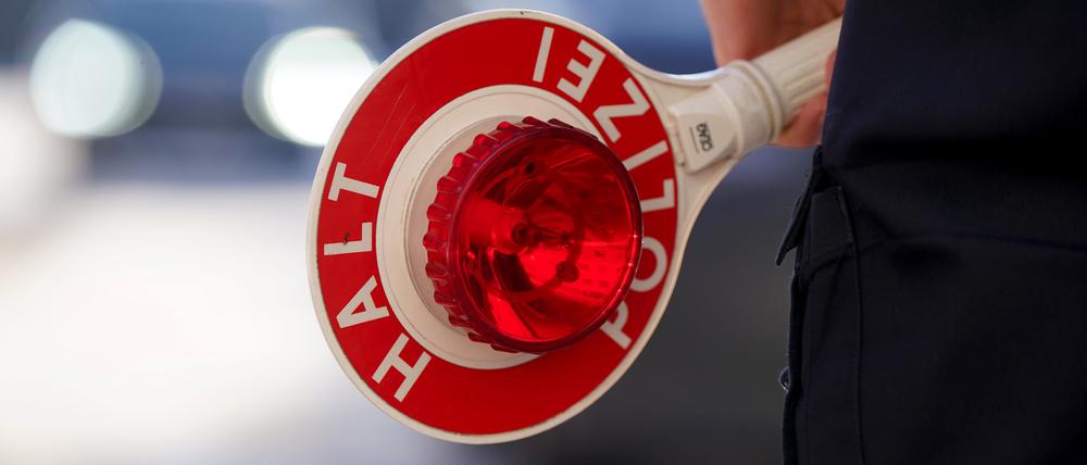 Ein Polizist hält eine Anhaltekelle in der Hand.