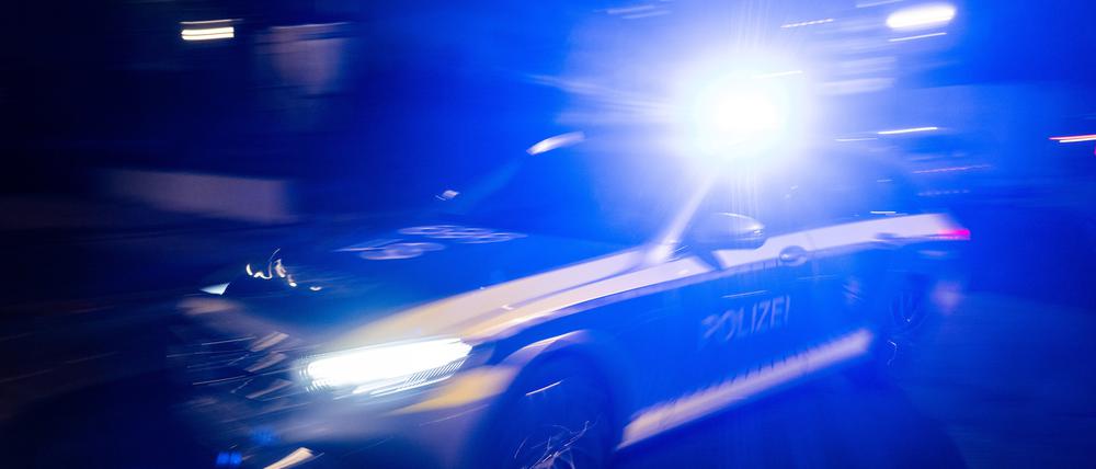 ILLUSTRATION - Ein Polizeifahrzeug fährt mit Blaulicht an einem Gebäude vorbei.
