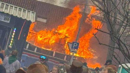 Ein Faschingswagen steht brennend auf einer Straße. 