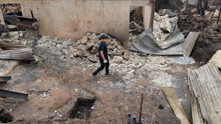EIn Kind läuft zwischen den Resten von abgebrannten Häusern entlang. 
