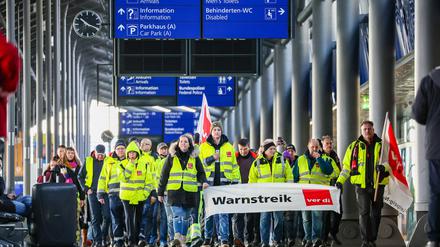 Beschäftigte der Mitteldeutschen Flughafen AG gehen während eines Warnstreiks durch den Flughafen Leipzig/Halle. 