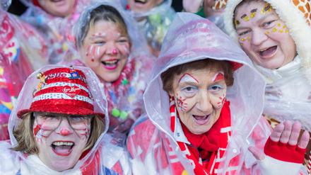 Karnevalisten mit Regenschutz feiern an Weiberfastnacht die Eröffnung des Straßenkarnevals auf dem Alter Markt. 