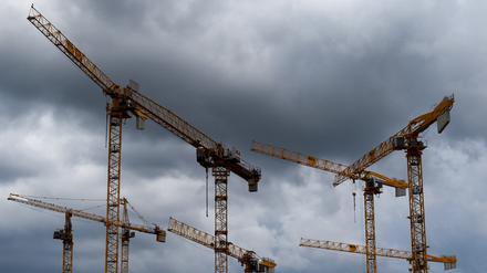 Kräne einer Baustelle sind vor dunklen Wolken zu sehen.