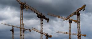Kräne einer Baustelle sind vor dunklen Wolken zu sehen.