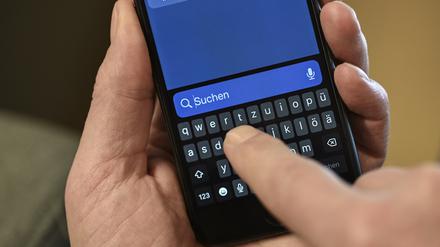 Ein Mann hält seinen Finger über das Suchfeld seines Smartphones. 