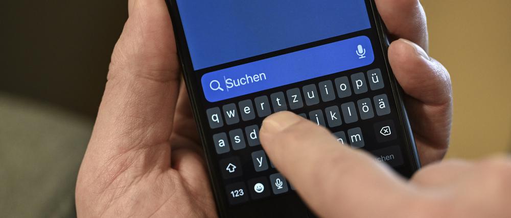 Ein Mann hält seinen Finger über das Suchfeld seines Smartphones. 