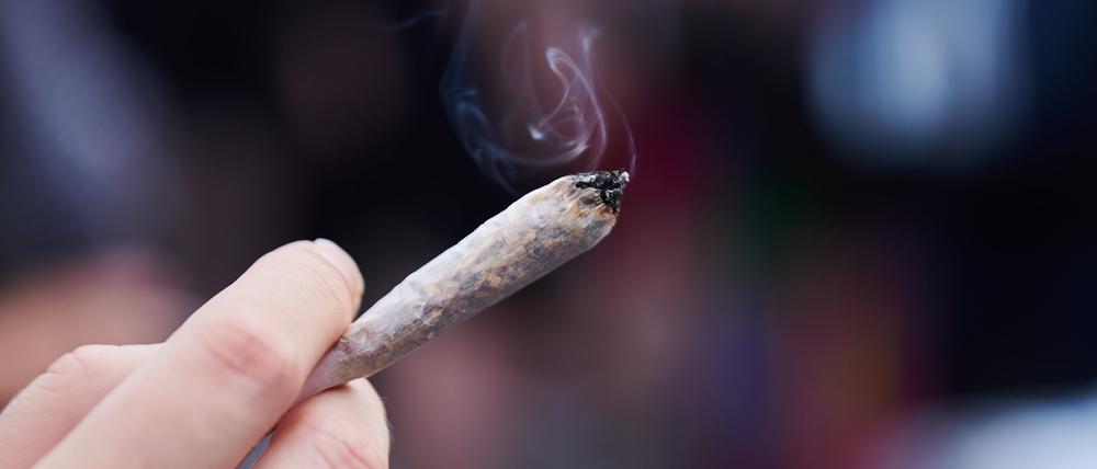 Eine Frau hält einen Joint in der Hand.