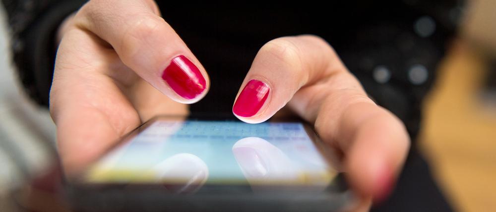 Eine Frau tippt auf einem Smartphone. (Symbolbild)