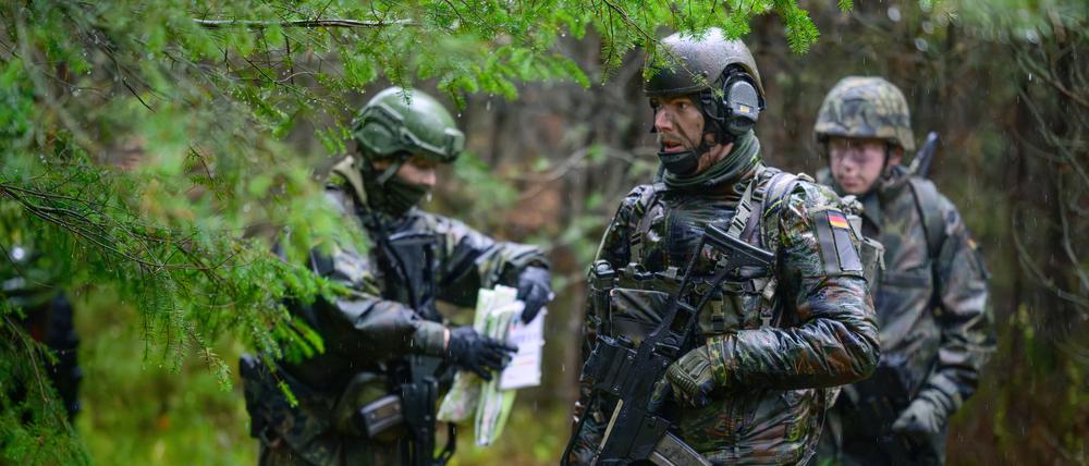 Soldaten der Bundeswehr stehen bei Regen während einer Übung im Wald.