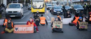 ARCHIV - 10.01.2024, Berlin: Aktivisten der Klimaschutzgruppe Letzte Generation sitzen bei einer Straßenblockade mit Schildern mit aufgemalten Traktoren auf der Straße. Aktivisten nehmen damit Bezug auf die Aktionswoche der Landwirte. (zu dpa: «Gericht: Straßenblockaden von Klimaaktivisten sind Nötigung») Foto: Sebastian Gollnow/dpa +++ dpa-Bildfunk +++