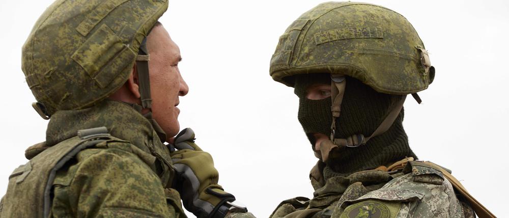 Ein russischer Ausbilder kleidet einen russischen Rekruten während einer militärischen Trainingseinheit korrekt an.