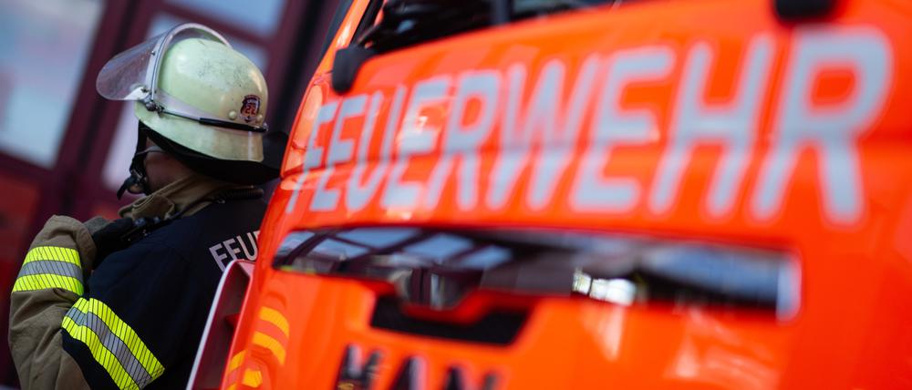 Ene Einsatzkraft der Feuerwehr steht neben einem Einsatzfahrzeug der Feuerwehr.