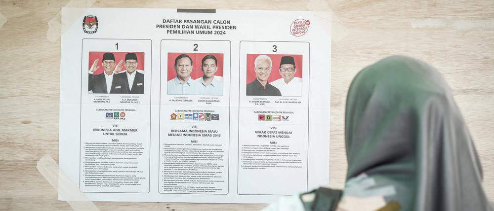 Eine Frau schaut sich eine Kandidatenliste für die Wahl in Indonesien an. Der Ex-General Prabowo könnte die Wahl mit hohem Vorsprung gewinnen. 
