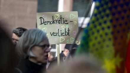 Eine Teilnehmerin einer Demonstration hält am Hauptbahnhof ein Schild mit der Aufschrift «Demokratie verliebt» hoch. 