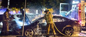 Feuerwehrleute löschen ein brennendes Auto in der Weserstraße in Berlin-Friedrichshain. 