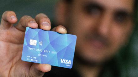 Ein Geflüchteter hält eine Debitcard in der Hand. 