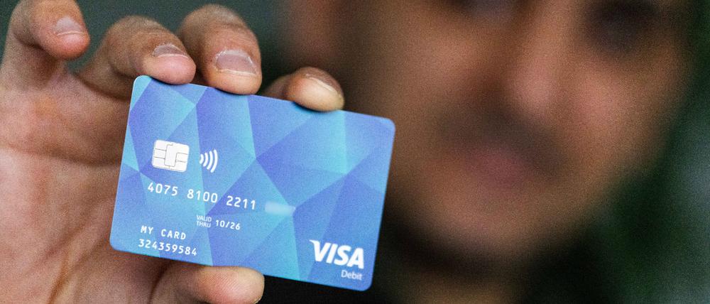 Ein Geflüchteter hält eine Debitcard in der Hand.