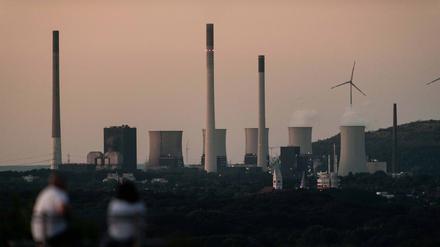 Die Kühltürme des Steinkohlekraftwerks von Uniper in Scholven nach Sonnenuntergang, während Personen auf einer Bank auf der Halde Tetraeder sitzen. Der Bund unterstützte Uniper mit einem milliardenschweren Rettungspaket.