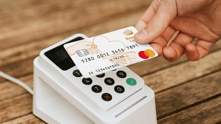 Eine Person zahlt mit einer Bezahlkarte an einem Terminal.