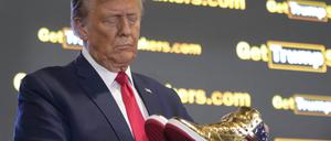 Der republikanische Präsidentschaftskandidat und ehemalige Präsident Donald Trump hält goldene Trump-Sneakers auf der Sneaker Con Philadelphia, einer Veranstaltung für Sneakersammler, in Händen. 