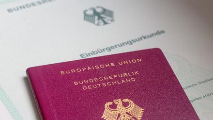 Eine Einbürgerungsurkunde der Bundesrepublik Deutschland und ein deutscher Reisepass liegen auf einem Tisch. (Symbolbild)