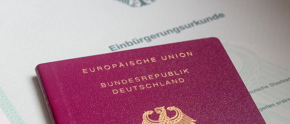 Eine Einbürgerungsurkunde der Bundesrepublik Deutschland und ein deutscher Reisepass liegen auf einem Tisch. (Symbolbild)