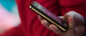 Eine Schülerin hält ein mobiles Telefon in der Hand. 