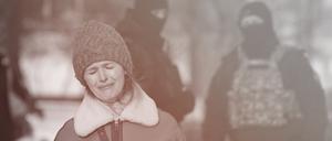 Zwei Polizisten beobachten eine weinende Frau, die dem verstorbenen Kremlgegner Alexej Nawalny an einem Denkmal in St. Petersburg gedenkt.