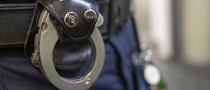 Eine Handschelle hängt am Gürtel eines Polizisten.