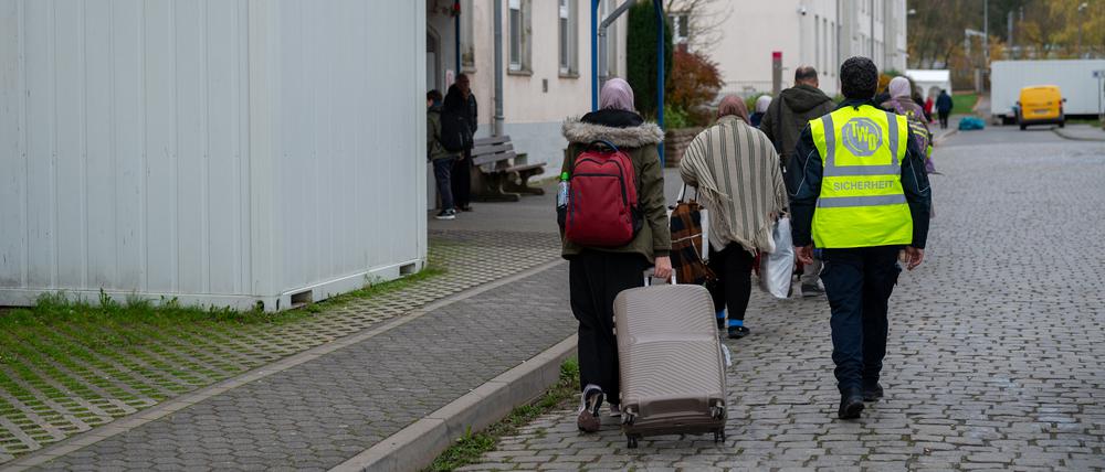 Neu angekommene Flüchtlinge gehen mit ihren Koffern in eines der Wohnhäuser der Aufnahmeeinrichtung für Asylbegehrende (AfA) in Trier.