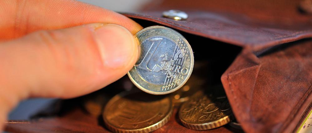 Eine Hand nimmt am 22.01.2010 eine Euro-Münze aus einem Geldbeutel, in dem sich weitere Münzen befinden.