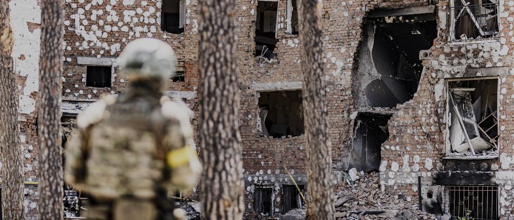 Ein ukrainischer Soldat steht vor einem zerstörten Gebäude in Irpin (Symbolbild)