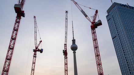 Der Berliner Fernsehturm am Alexanderplatz im Bezirk Mitte waehrend der Abenddaemmerung mit Baukraenen auf der Baustelle des Covivio-Hochhaus. 