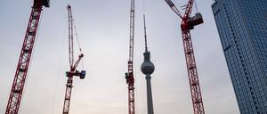 Der Berliner Fernsehturm am Alexanderplatz im Bezirk Mitte waehrend der Abenddaemmerung mit Baukraenen auf der Baustelle des Covivio-Hochhaus. 