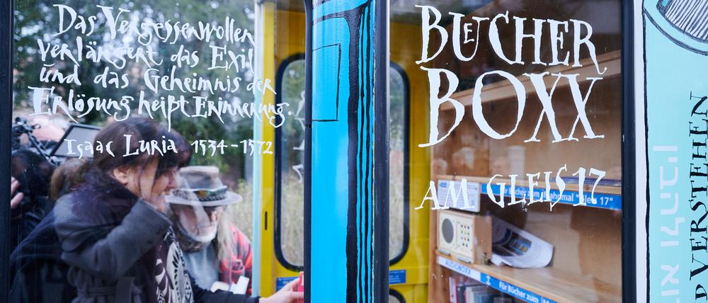 Personen stellen Bücher in die neue „·Bücherbox“ am S-Bahnhof Grunewald.