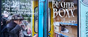 Personen stellen Bücher in die neue „·Bücherbox“ am S-Bahnhof Grunewald.