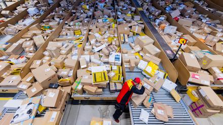 Ein Paketzusteller sortiert und räumt in einer Zustellbasis von Deutsche Post DHL Pakete in ein Zustellfahrzeug.