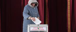 Eine Frau wirft ihren Wahlzettel in eine Urne.