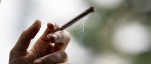 Eine Hand hält einen qualmenden Joint.