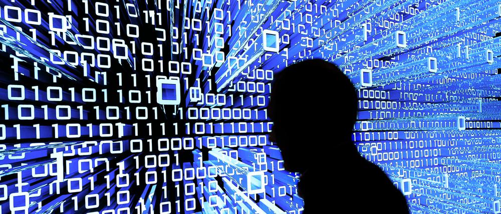 ARCHIV - 16.03.2015, Niedersachsen, Hannover: Ein Messebesucher geht an einem Leuchtdisplay auf der CeBIT vorbei.