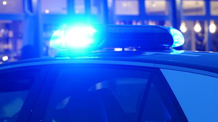 Ein Blaulicht leuchtet auf dem Dach eines Polizeiautos während einer Polizeiabsperrung. 