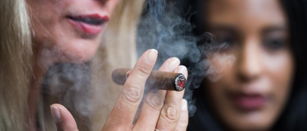 Zwei Models rauchen auf der Messe Intertabac am Stand von Habanos eine Zigarre. 