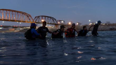 Migranten laufen Hand ind Hand durch den Rio Grande River, um aus Mexiko nach Eagle Pass in Texas zu gelangen.   