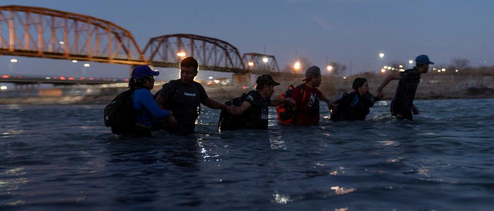 Migranten laufen Hand ind Hand durch den Rio Grande River, um aus Mexiko nach Eagle Pass in Texas zu gelangen.