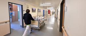Ein Pfleger schiebt ein Bett mit Patienten.