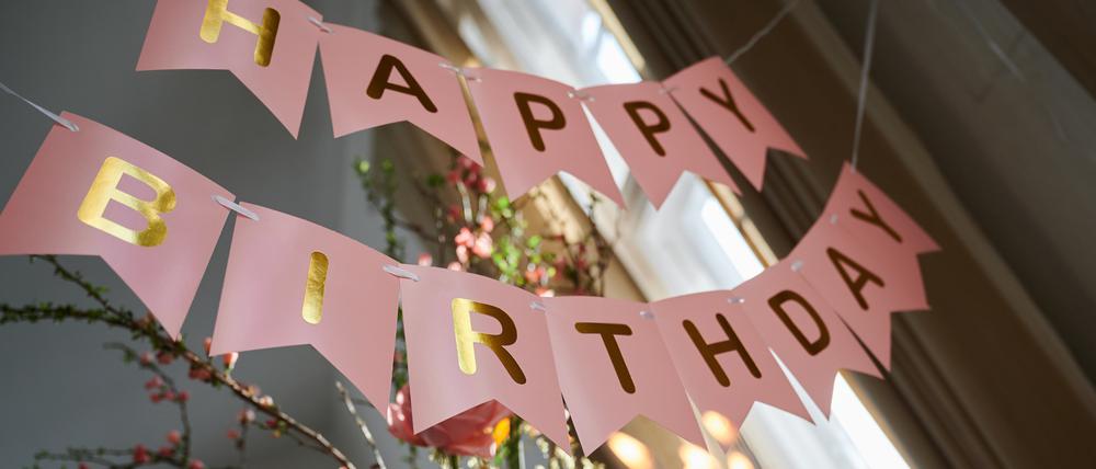 „Happy Birthday· steht auf einer Girlande, die über einem Geburtstagstisch hängt.