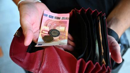 Ein Kellner eines Restaurants hält einen Geldbeutel in der Hand, während er in der anderen Hand Geld hält.
