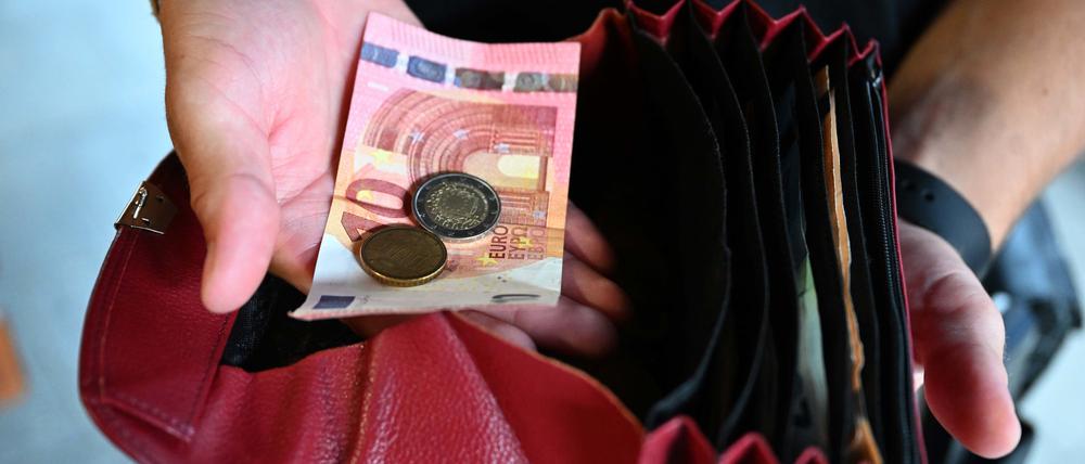 Ein Kellner eines Restaurants hält einen Geldbeutel in der Hand, während er in der anderen Hand Geld hält.
